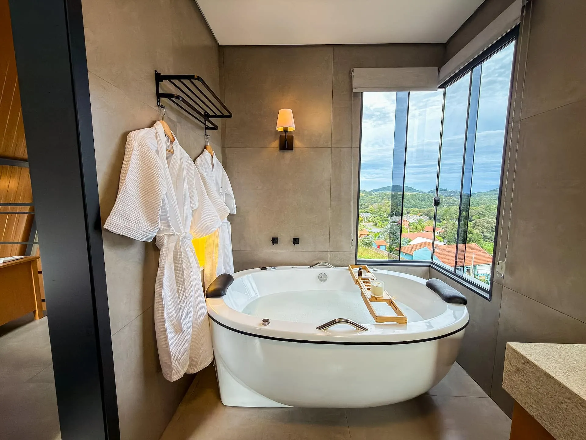 Banheira de hidromassagem junto à janela, com roupões e vista do vale