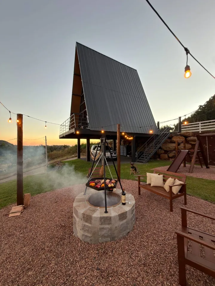Firepit com grelha suspensa e varal de luzes ao entardecer