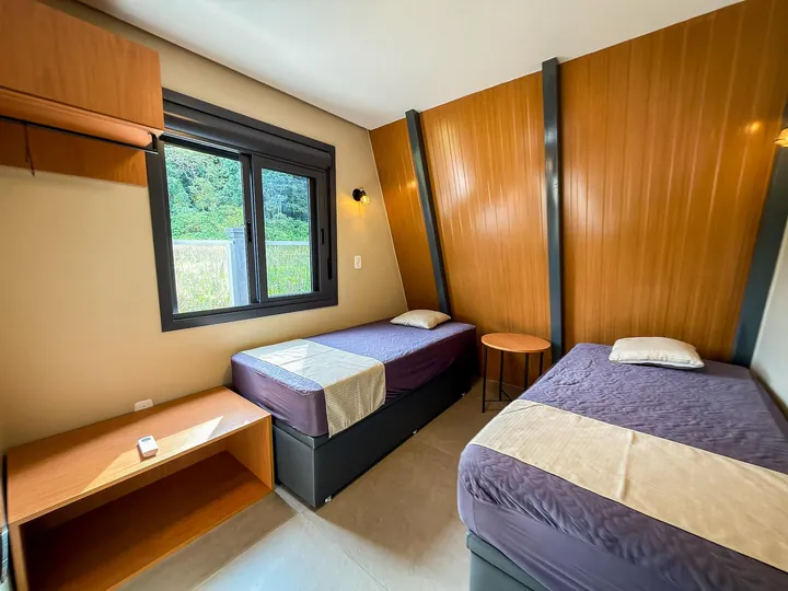 Quarto com duas camas de solteiro e janela para o verde