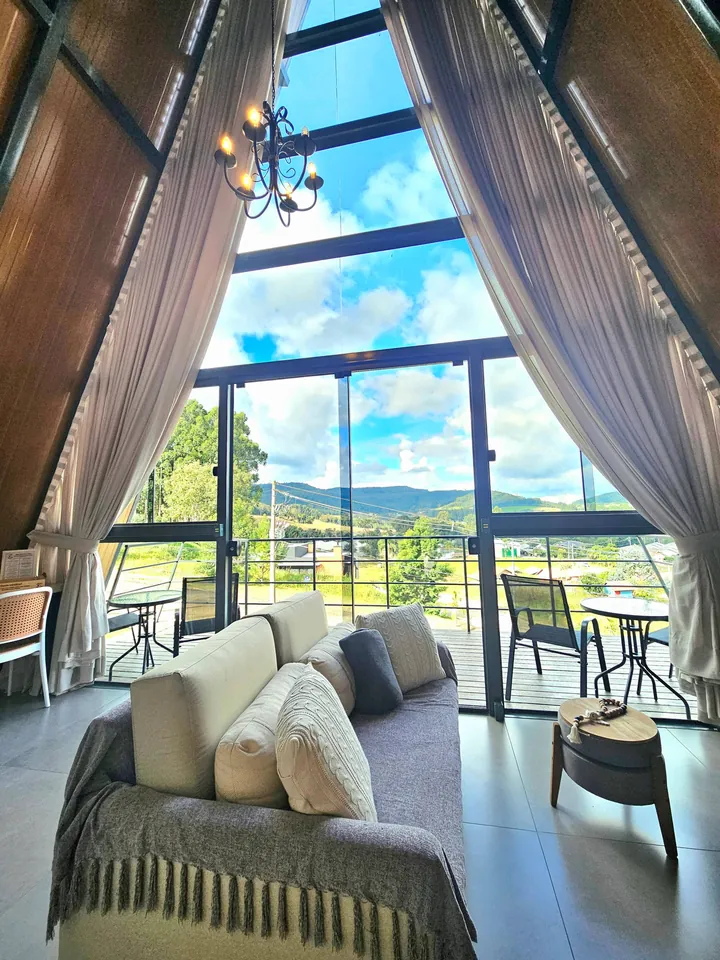 Sala com sofá diante da parede de vidro em A e a vista da serra