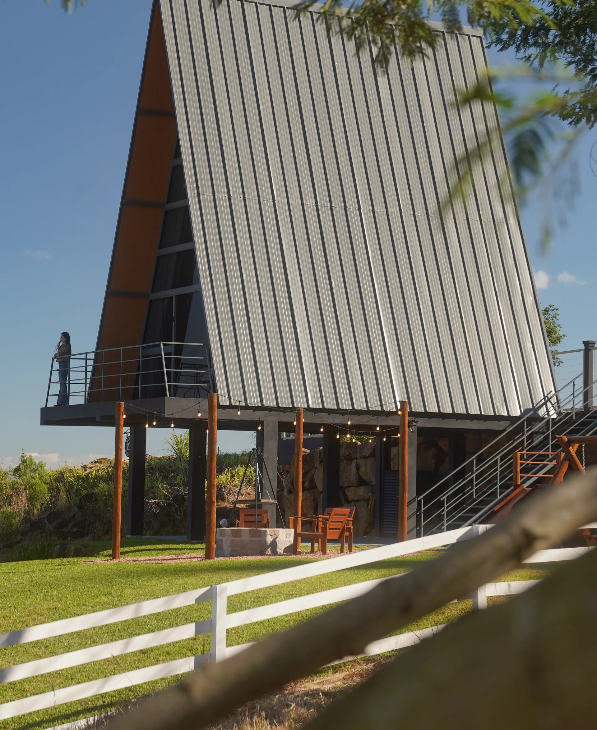 A cabana A-frame da Reserva Linha Imperial vista do gramado, sob o céu azul
