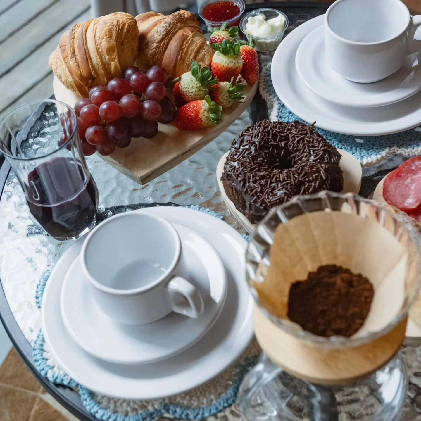 Mesa de café com croissants, frutas e café coado